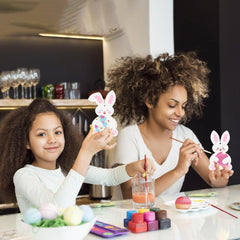 Two children painting Easter bunny figures at a table.