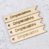 Four wooden tags with 'Congratulations' text on a gray surface