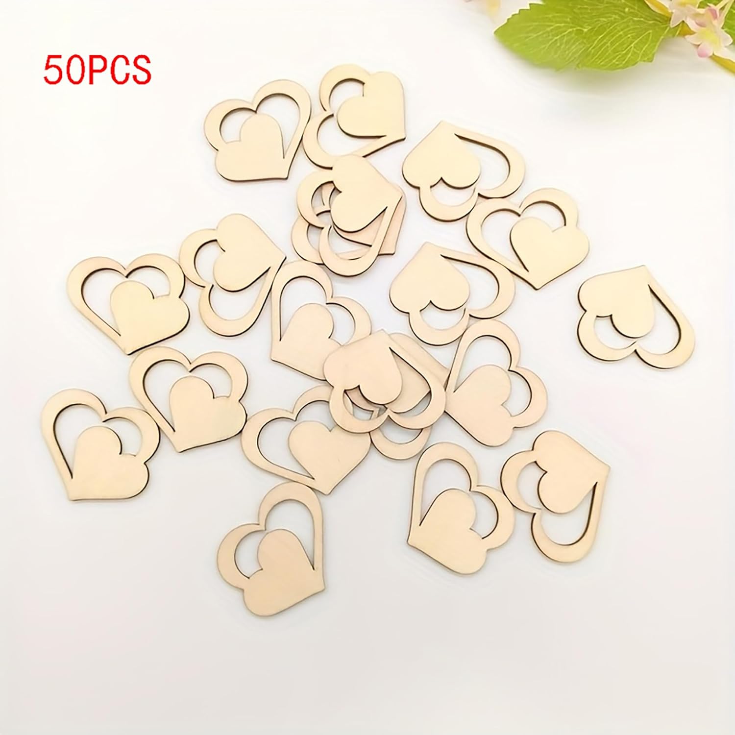50 wooden heart-shaped objects on a white background with green leaves.
