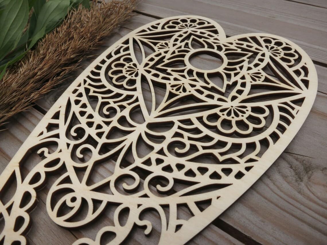 Decorative wooden heart with intricate cut-out patterns on a wooden surface.