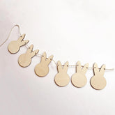 Wooden bunny shapes on a string against a light pink background