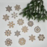 Decorative snowflake ornaments on a white surface with a branch of pine tree.