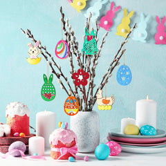 Decorative Easter setup with colorful eggs, candles, and a vase on a light blue background.