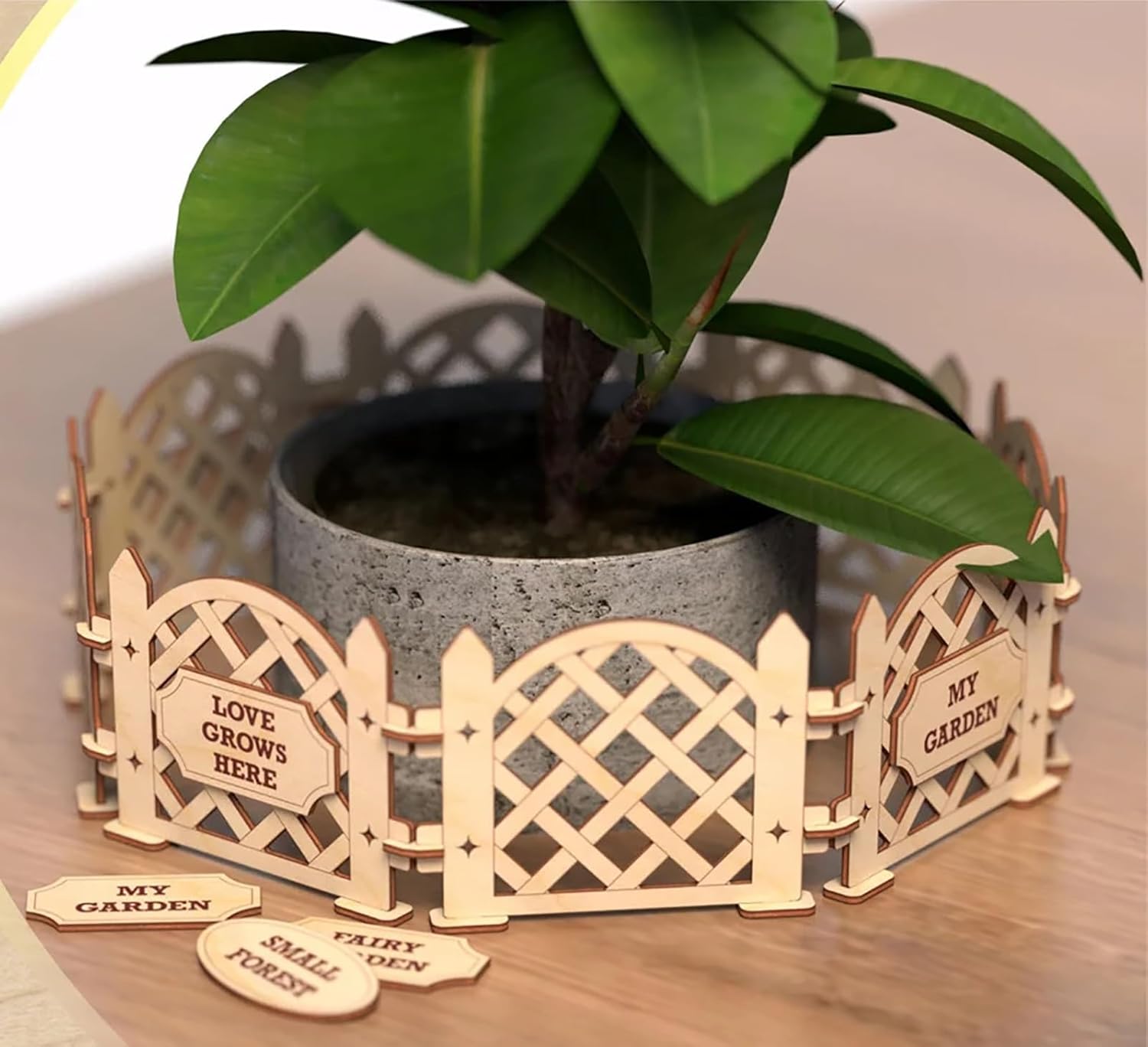 Decorative wooden garden fence around a potted plant with small signs on a wooden surface.