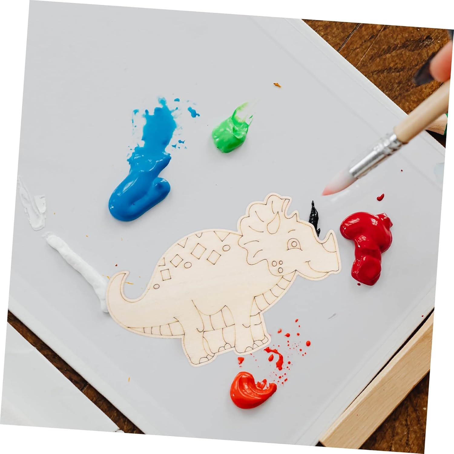 Wooden dinosaur puzzle on a white board with paint and a brush