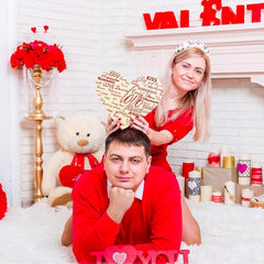 Couple in Valentine's Day-themed setting with decorations and 'I love you' sign.