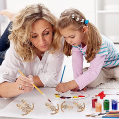 Woman and young girl painting together on a table with art supplies.