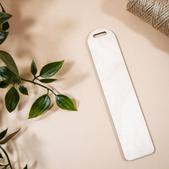 White rectangular object on a beige surface with green leaves and twine in the background