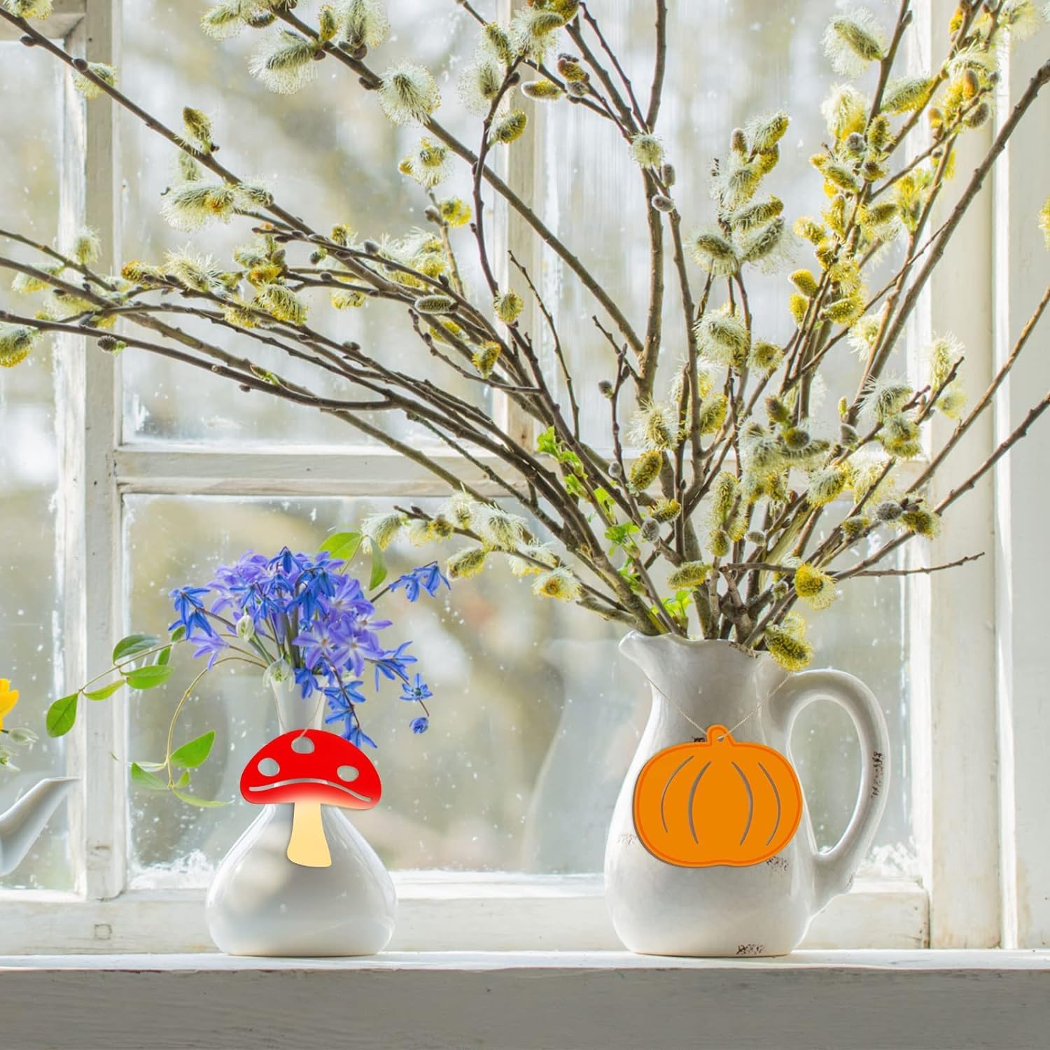 Decorative vases with floral arrangements and pumpkins on a windowsill.