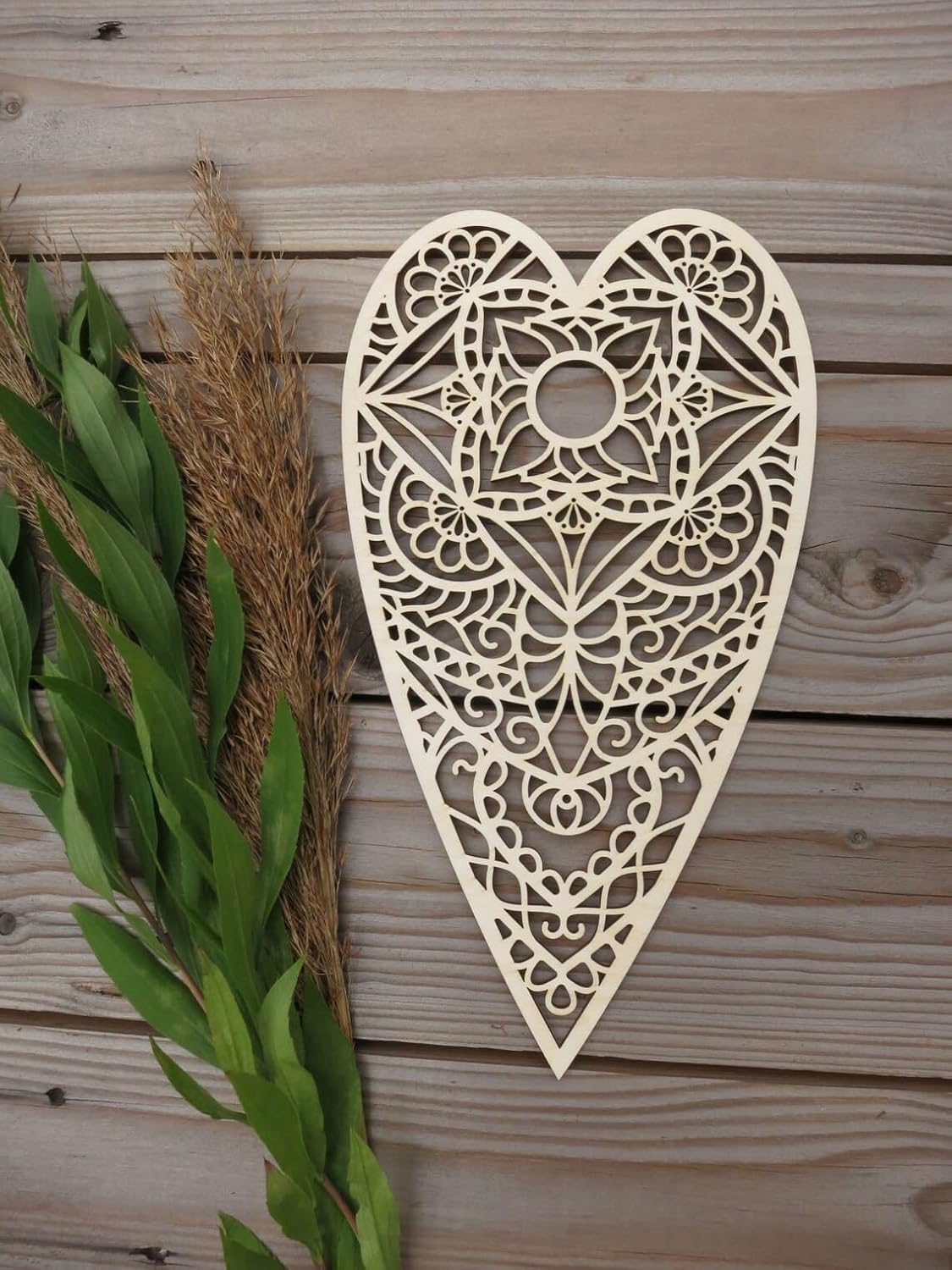 Decorative heart-shaped wooden wall art with intricate patterns on a wooden background.