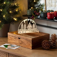 Wooden box with 'Merry Christmas' decoration on a table with festive decor.