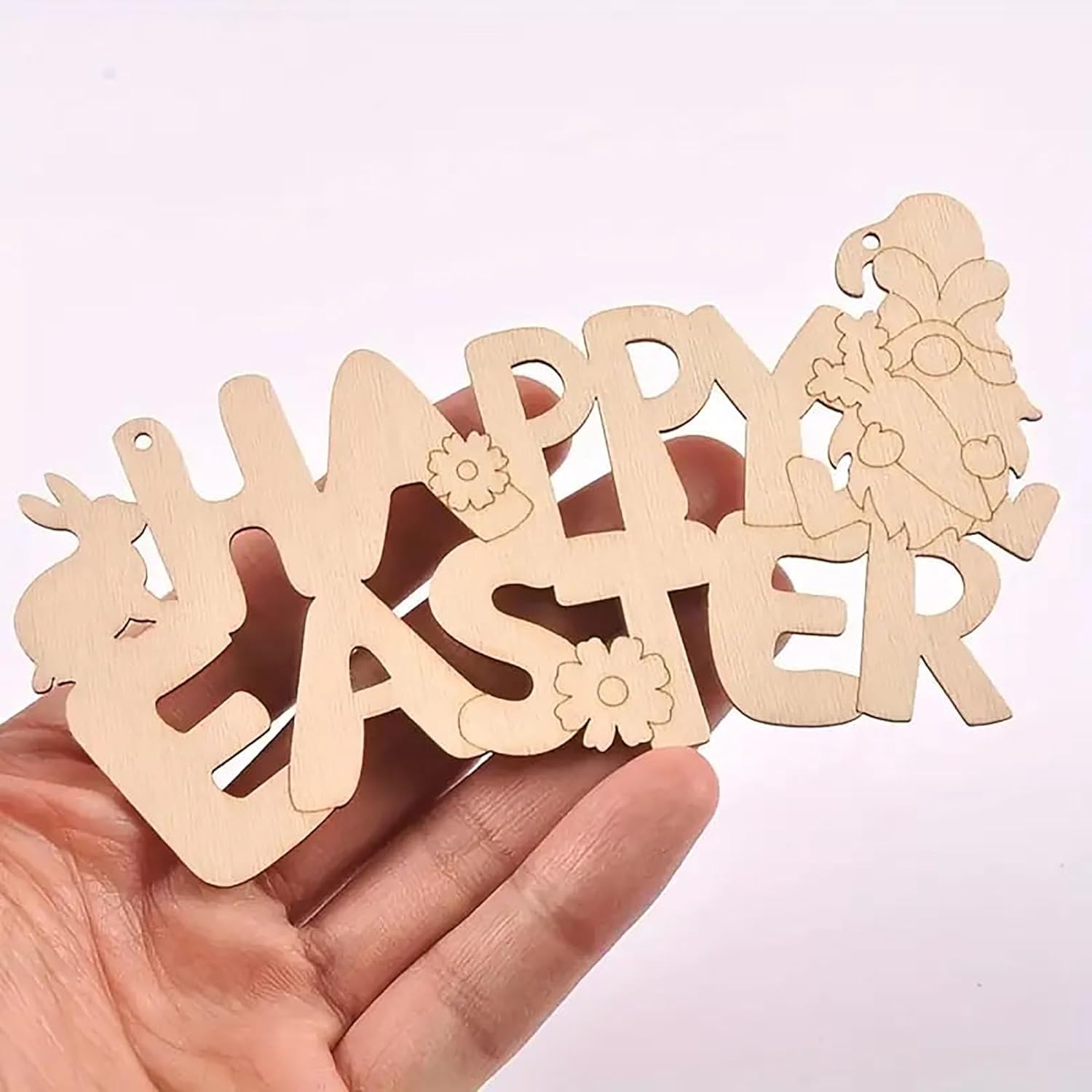 Wooden 'Happy Easter' decoration held in a hand against a light pink background