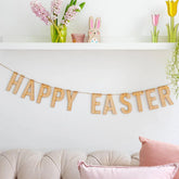 Happy Easter banner on a white wall with decorative items above a sofa.