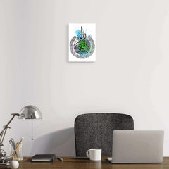 Decorative wall art with Arabic calligraphy on a white wall above a desk with a laptop and lamp.