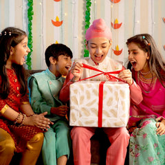 Children in traditional attire opening a gift box with excitement against a festive background.