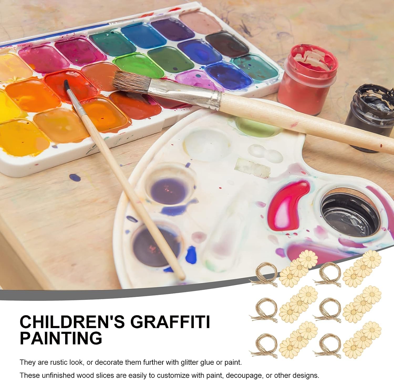 Art supplies including a watercolor set, paintbrushes, and children's graffiti painting materials on a wooden surface.