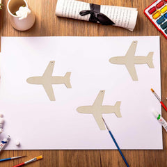 Three airplane shapes on a piece of paper with art supplies on a wooden table.
