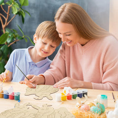 Woman and child painting wooden crafts at a table with art supplies.