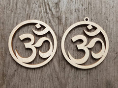 Two wooden OM symbol pendants on a wooden surface