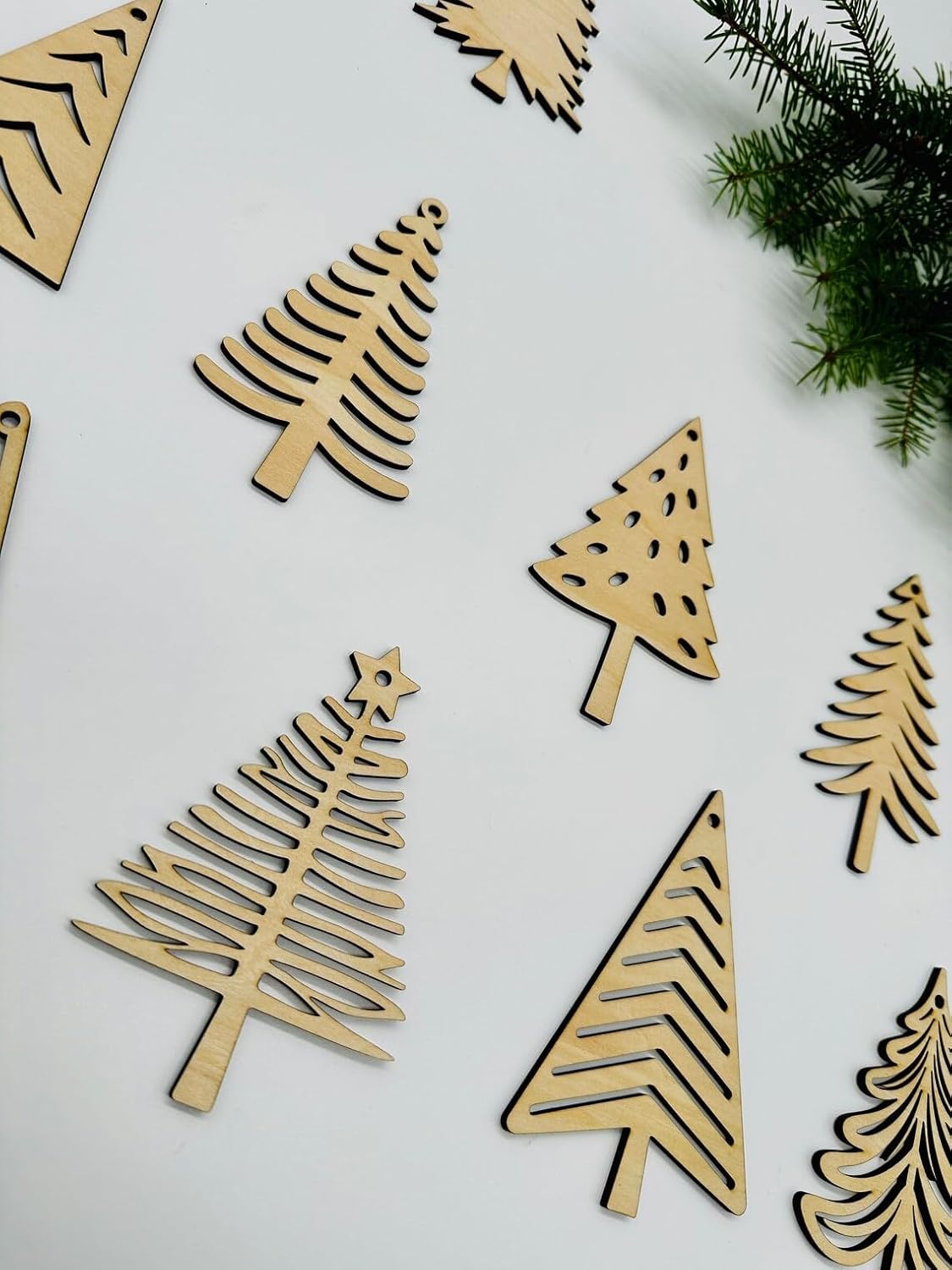 Wooden Christmas tree decorations on a white background with greenery.