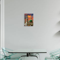 Modern glass dining table with chairs against a white wall with a framed picture of a mosque.