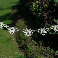 Bee-shaped decorative garland hanging outdoors among greenery