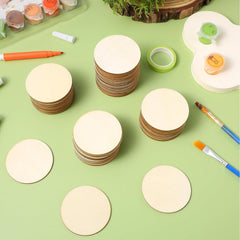 Stacks of round wooden discs on a green surface with painting supplies.