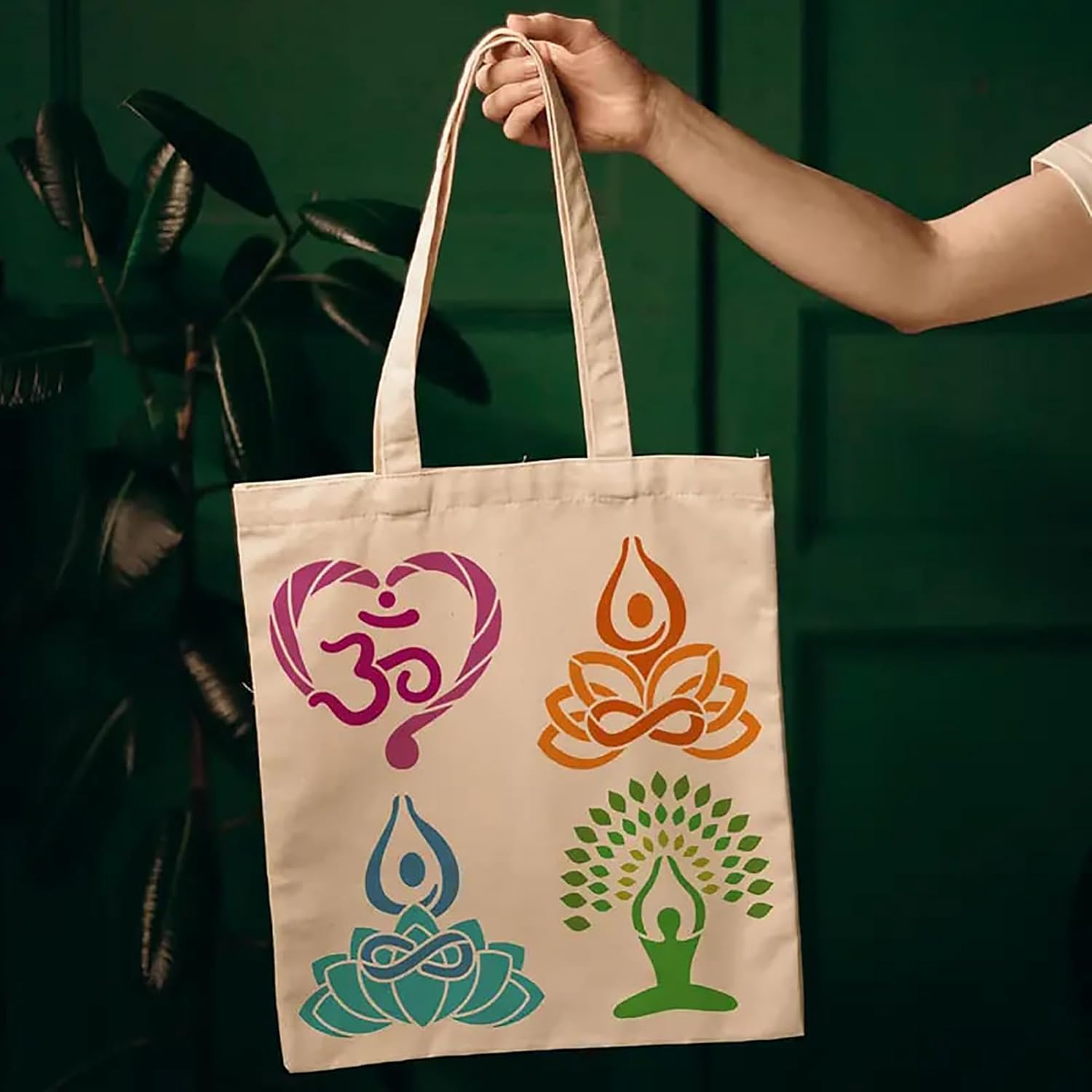 Tote bag with yoga-themed designs held by a hand against a dark green background