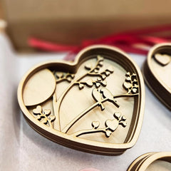 Heart-shaped wooden ornament with bird design on a light background