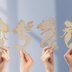 Wooden mermaid ornaments held by hands against a light blue background