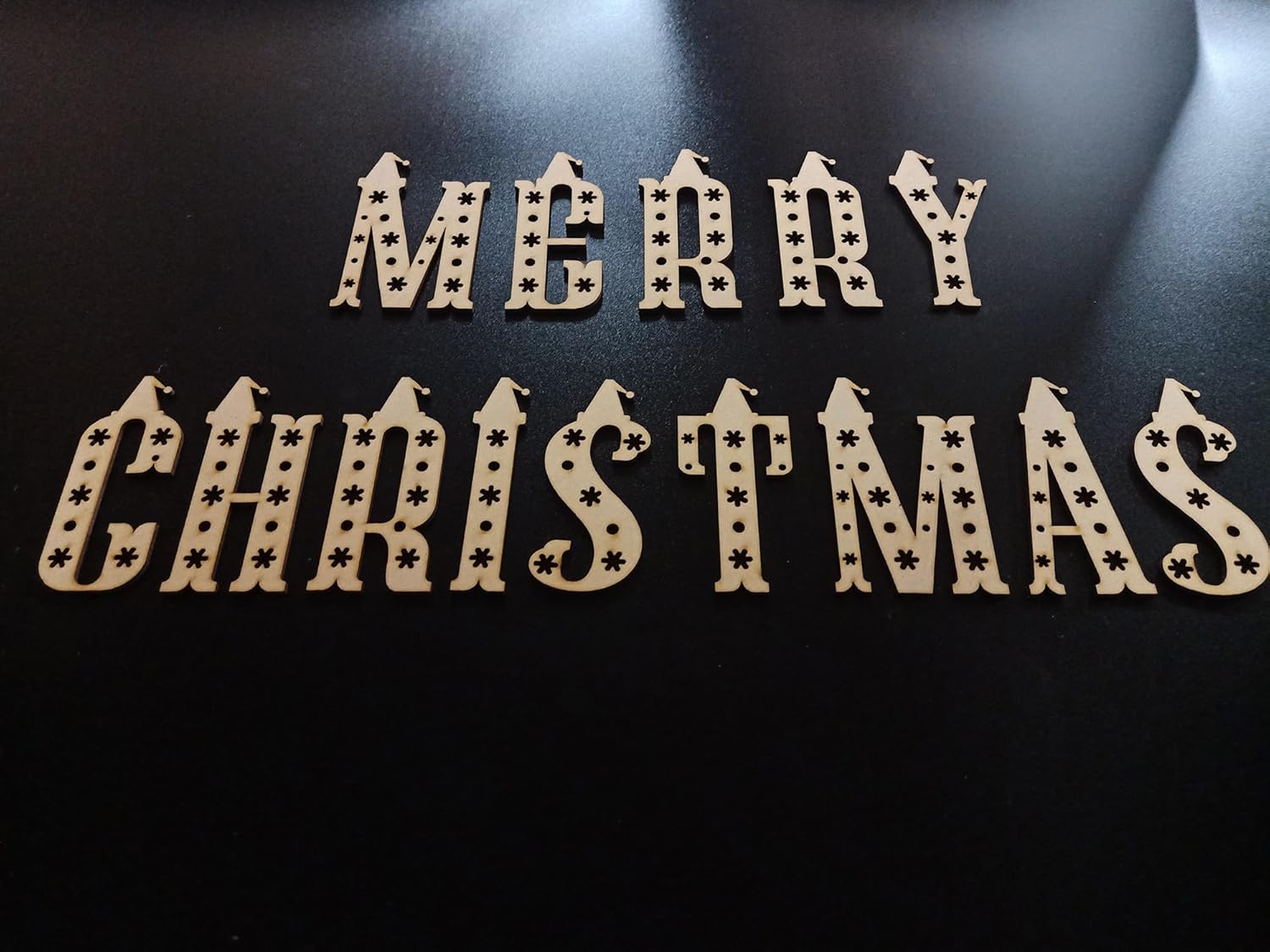 Wooden 'Merry Christmas' decoration on a black background