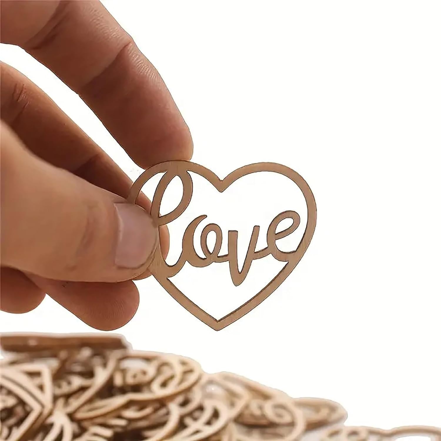 Heart-shaped wooden ornament with 'love' engraving held by a hand against a white background