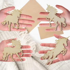 Unicorn-shaped wooden cutouts held in hands against a white background