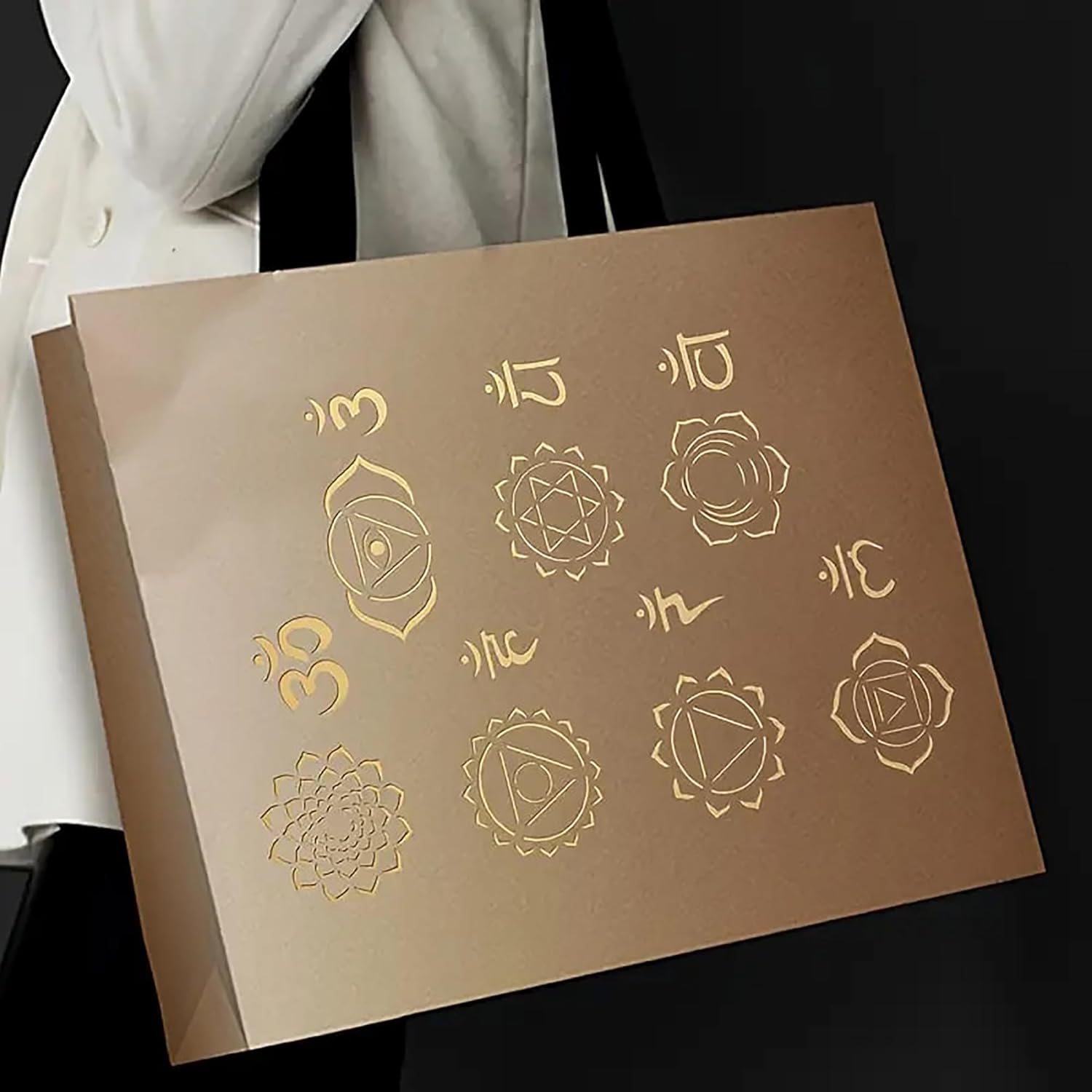 Brown box with gold symbols held by a person wearing a white garment.
