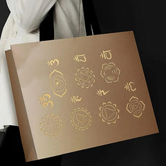 Brown box with gold symbols held by a person wearing a white garment.