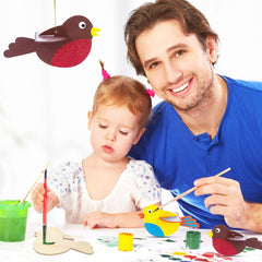 Man and child painting wooden birds with colorful paints on a white background