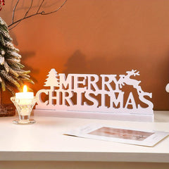 Decorative 'Merry Christmas' sign with a candle and card on a table.