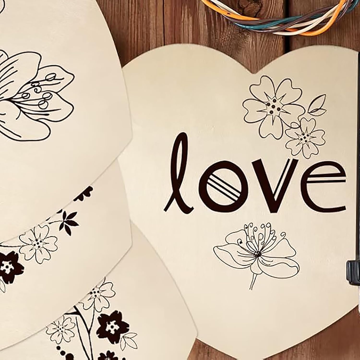 Heart-shaped card with 'love' and floral designs on a wooden surface