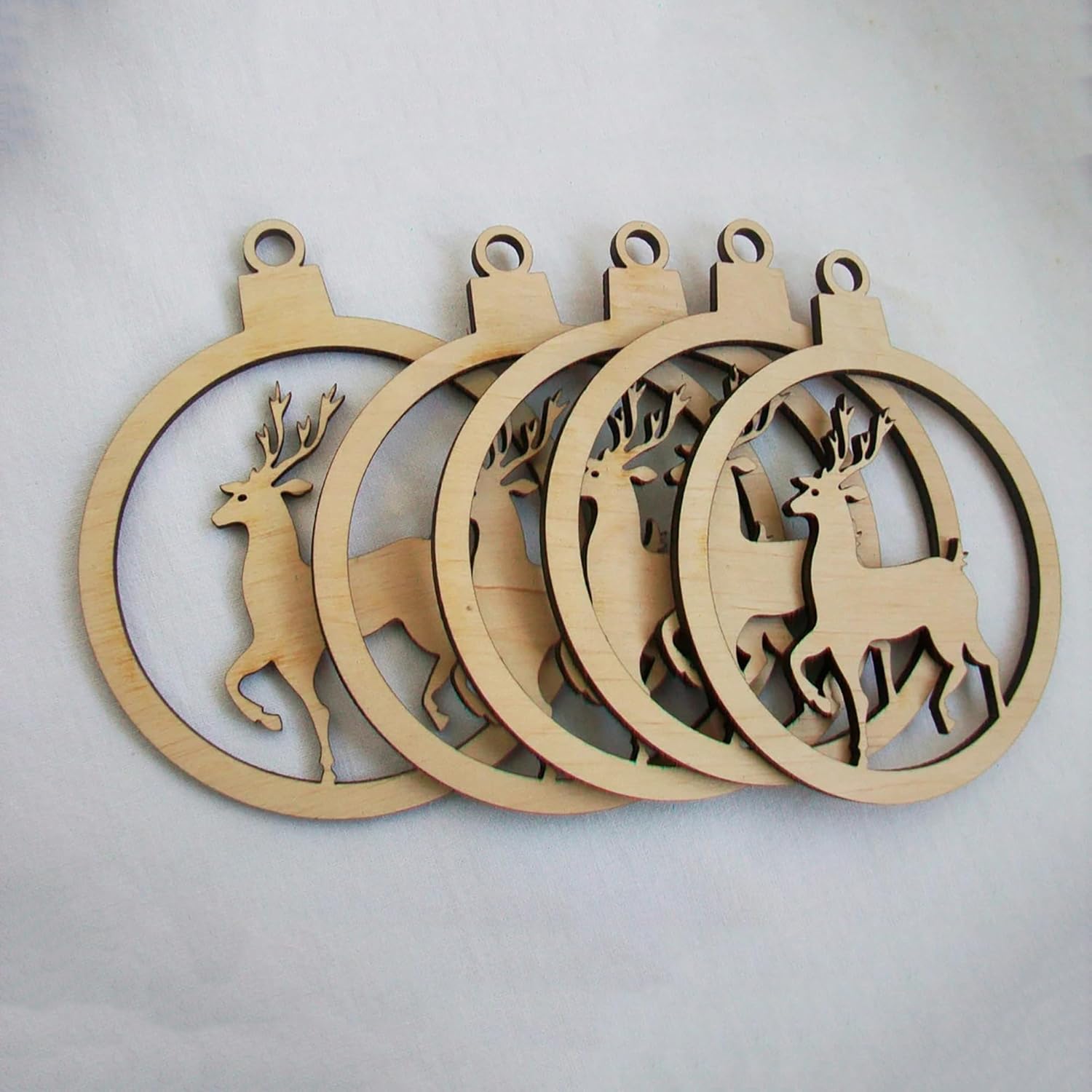 Set of wooden Christmas ornaments with deer designs on a light gray background