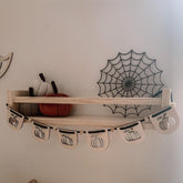 Wooden shelf with decorative items including pumpkins and a spider web design on the wall.