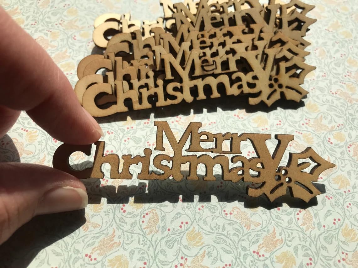 Wooden 'Merry Christmas' decorations held by a hand on a floral background