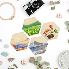 Hexagonal coasters with scenic designs on a white surface with decorative elements.
