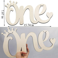 Wooden letter spelling 'one' with a crown design, held by a hand against a gray background.