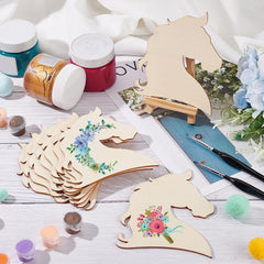 Wooden horse shapes with floral designs on a table with paint jars and brushes.