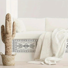 Decorative cactus and white blanket on a white sofa with a white wall background
