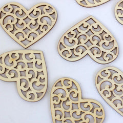 Wooden heart-shaped decorations with intricate cut-out patterns on a white background
