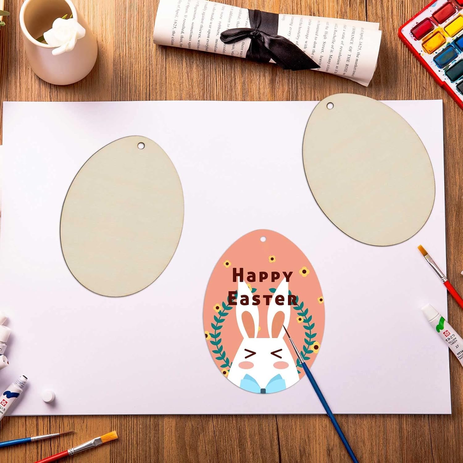 Easter-themed craft project with painted eggs and 'Happy Easter' text on a wooden table.