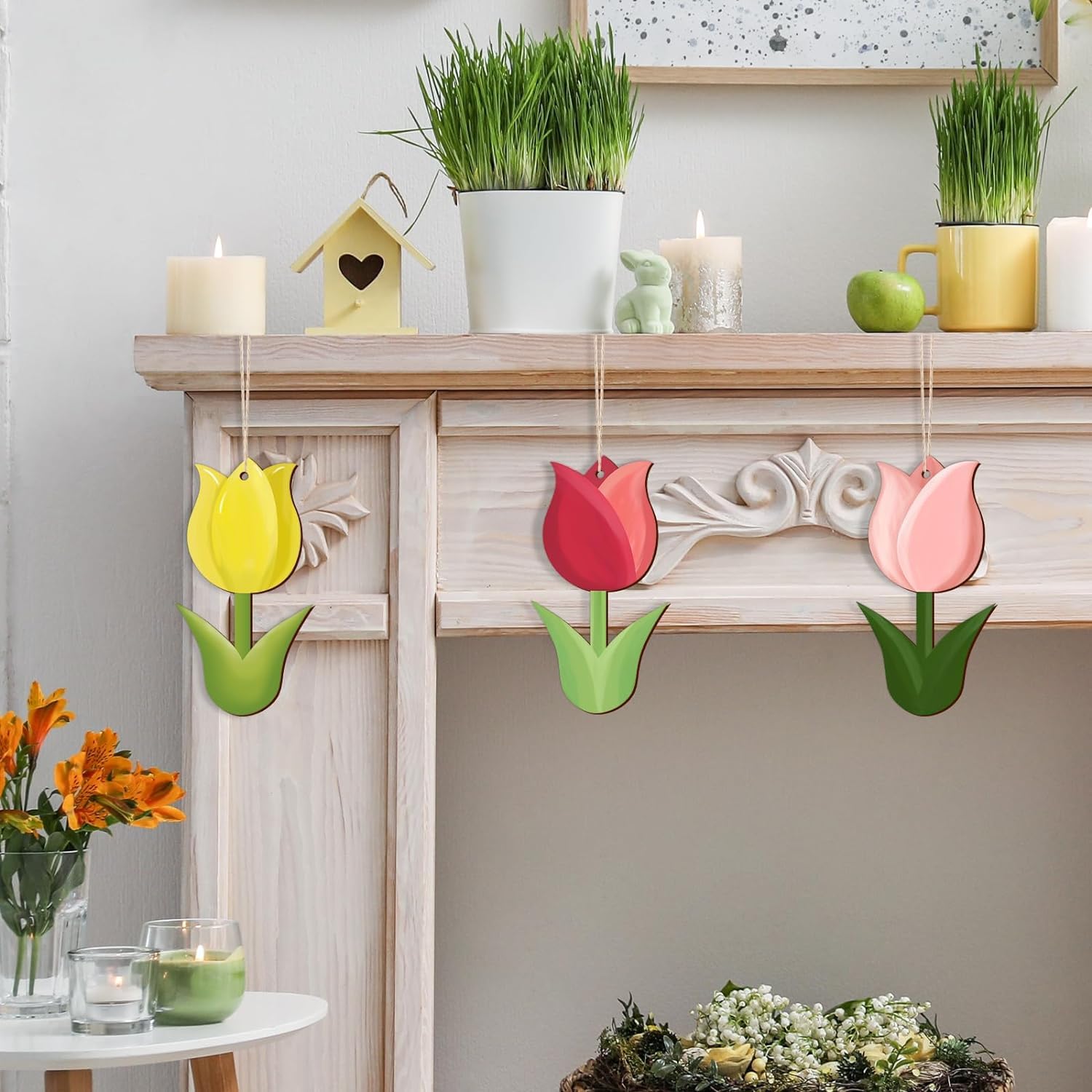 Decorative tulip-shaped items hanging on a fireplace mantle with candles and plants.