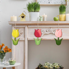 Decorative tulip-shaped items hanging on a fireplace mantle with candles and plants.