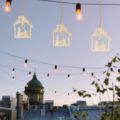Decorative nativity scene cutouts hanging against a cityscape with lights.
